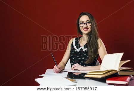 Attractive brunette student girl in glasses, table workplace with books and tablet pc