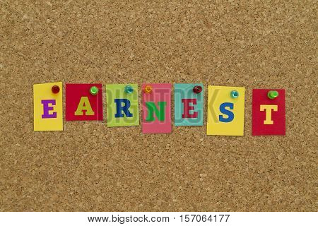 Earnest word written on colorful sticky notes pinned on cork board.
