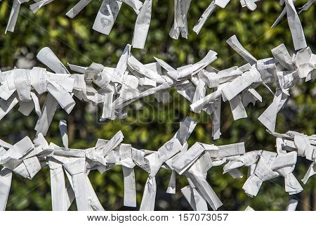 Random fortunes written on paper strips and tied to rope fence for good luck Kyoto Japan