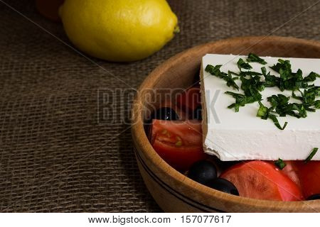 Greek salad with feta cheese and vegetables on wooden plate