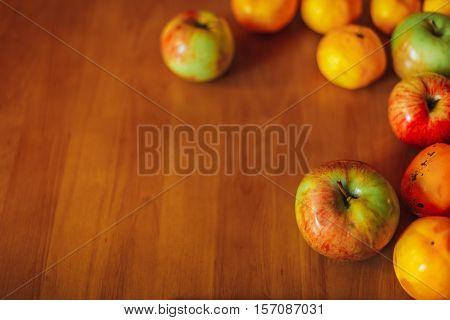 Healthy food background on old wooden table. Fruit. Apples, tangerines, persimmons.