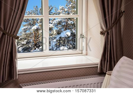 Window with curtains with snowy pine trees