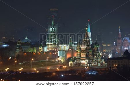 Kremlin wall, Spassky Tower being restored, Vasilevsky descent and St Basil Cathedral in Moscow, Russia at night