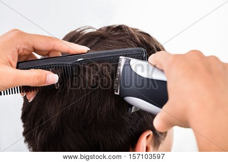 Close-up Of A Hairdresser Cutting Man's Hair With Electric Trimmer At Salon
