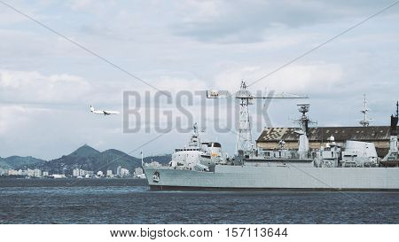 View of bay in Rio de Janeiro with military ship crane and landing airplane cloudy summer day Brazil