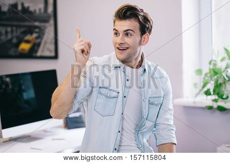 Looking from the smiling men in the office. Stylish designer at work. Focused on his job businessman. White interior. Worker got idea