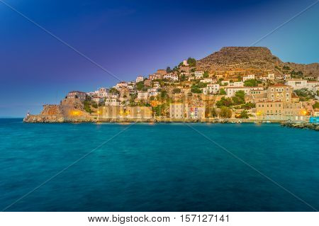 Hydra island in a summer evening in Greece. Beautiful landscape with sea and island at sunset lit with purple light.