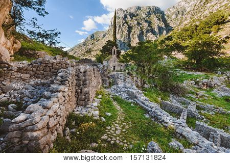 Ancient Serbian church ruins and mountain valley landscape near Kotor castle in Montenegro. Old mountain church and monastery in Kotor Bay region near hike path to Lovchen mountain. Saint Ivan chapel.