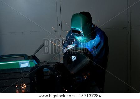 Welder working with electrode at semi-automatic arc welding.