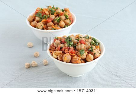 Indian vegetarian food channa chat, also known as chickpea or garbanzo curry, is eaten as a snack or is used as a side dish, in two bowls.