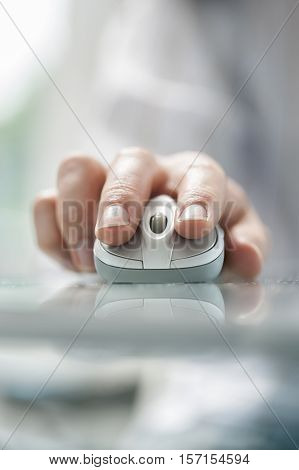 Man's hand using cordless mouse on glass table. Close up soft focus