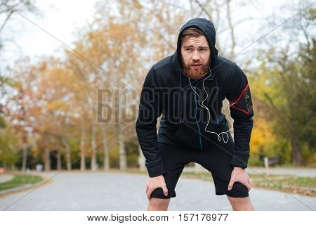 Front view of tired runner in park. looking away