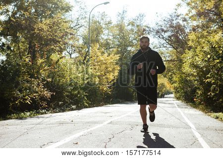 Front view of young runner in park. looking at camera