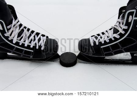Men's hockey skates and the puck on a snowy background