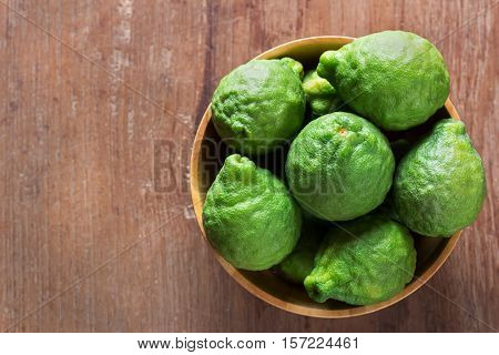 Close up fresh bergamot in wooden bowl on dark wood table background. bergamot on old wooden brown with copy space. (Bergamot or Kaffir lime)