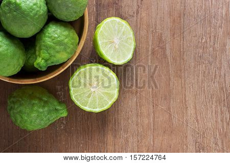 Close up fresh bergamot and bergamot slice in wooden bowls on dark wood table background. bergamot on old wooden brown with copy space. (Bergamot or Kaffir lime)