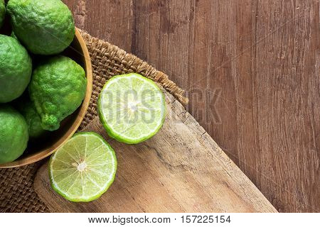 Close up fresh bergamot and bergamot slice in wooden bowl on dark wood table background. bergamot on old wooden brown with copy space. (Bergamot or Kaffir lime)