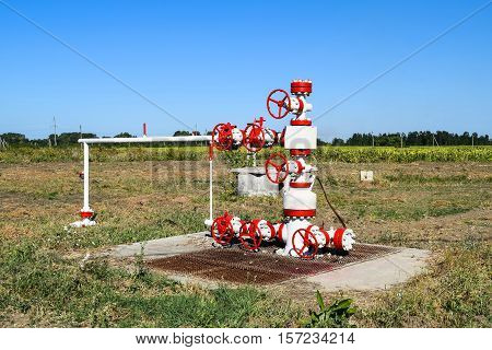 Oil Well In The Field, Painted In White And Red. Oil With Modern Equipment.