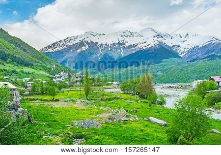 The green valley at the bank of Mestiachala river with the Svan towers on the distance Mestia Georgia.