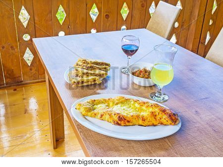 The dinner in Svan restaurant with Ajarian khachapuri (pie with cheese and egg) kubdari (Svan pie with meat) ajpsandal (vegetable saute) and local wine Mestia Georgia.