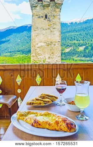 The dinner on the open terrace with Ajarian khachapuri (pie with cheese and egg) kubdari (Svan pie with meat) and local wine Mestia Georgia.
