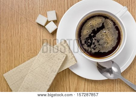 Coffee cup on a table, coffee beans and lump sugar around, studio shot