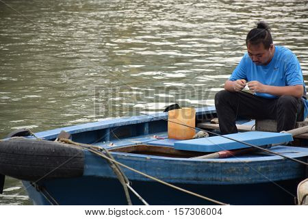 LANTAU ISLAND, HONG KONG, CHINA - NOVEMBER 19, 2016 - Unidentified asian boatman on his boat