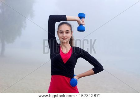 Young Sporty Woman Exercises With Dumbells During Fitness Training Outdoor