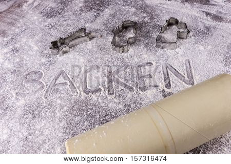 Baking (Backen) in German letters written in flour on the table