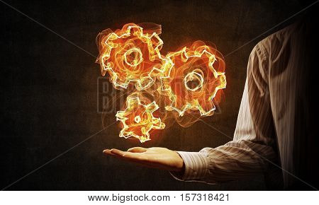 Hand of businessman presenting fire gear mechanism in palm