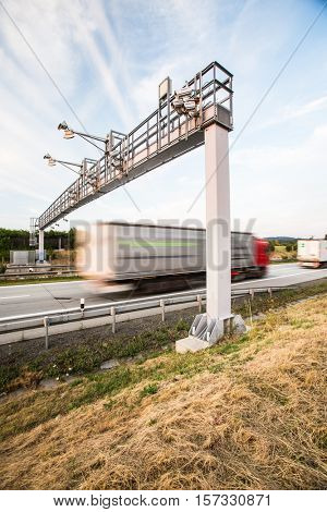 truck passing through a toll gate on a highway (motion blurred image; color toned image)