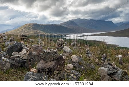Inukshuks along the borders of Scottish Loch Ness overshadowed by dark clouds