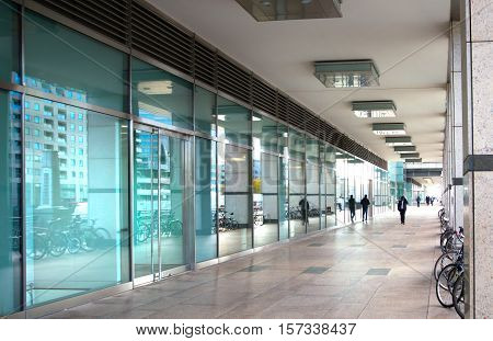 LONDON, UK - November 16, 2016: Canary Wharf, water side pass of office block with walking people and light in the end of the pass