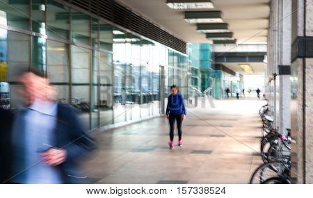 Abstract, blurred image of people walking via long tunnel with light at the background.