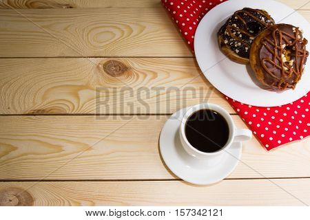 Cup of coffee with chocolate donuts on a rustic background