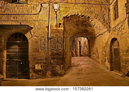 Pitigliano, Grosseto, Tuscany, Italy: picturesque old alley and underpass at night in the medieval village founded in Etruscan time