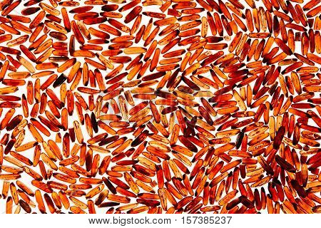 Red rice close-up on white background. Pattern wild brown unpolished rice for vegetarians.