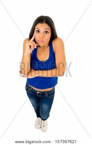 young attractive hispanic woman in casual top and jeans shrinking shoulders pointing her head thinking and wondering confused in doubt isolated on white background