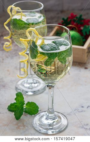 Spritzer cocktail with white wine mint and ice decorated with spiral lemon zest vertical