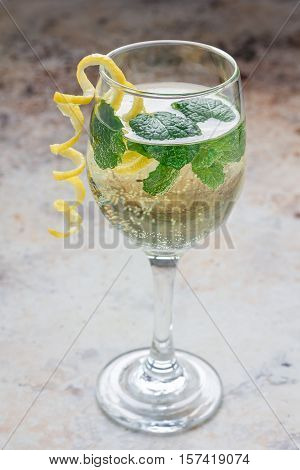 Spritzer cocktail with white wine mint and ice decorated with spiral lemon zest vertical