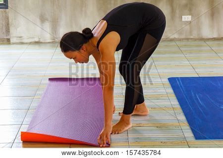 Woman rolling her mat in yoga class