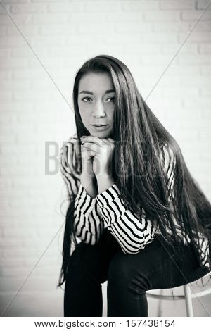 Portrait of a seated girl . Portrait in black and white. Low key.