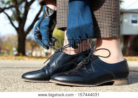 elegant woman in fashion wool gloves tying shoelaces