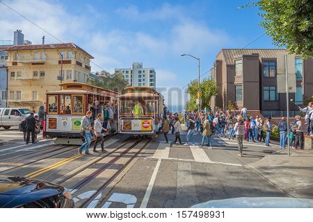 San Francisco, California, United States - August 16, 2016: two Cable Car tram, Powell-Hyde lines meet. Tourists crossing the intersection between Hyde and Lombard Street, popular touristic attraction