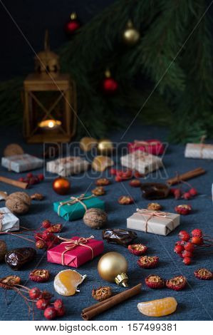 Christmas gifts, rowan, nuts, old lamp and pine branch with cones on dark surface
