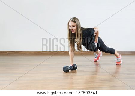 Young fit woman makes exercises with weight in gym class. Space for placing text .
