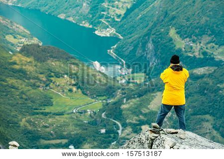 Tourism vacation and travel. Male tourist enjoying Geirangerfjord and mountains landscape from Dalsnibba viewpoint Norway Scandinavia.