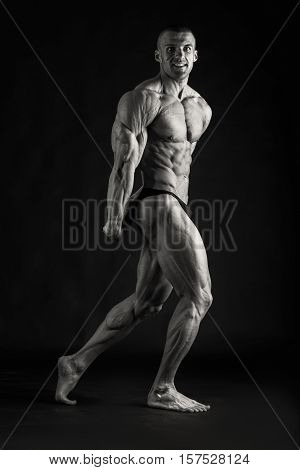 Bodybuilder posing in different poses demonstrating their muscles. Failure on a dark background. Male showing muscles straining. Beautiful muscular body athlete.