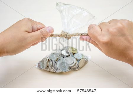 Woman tied rope to close a bag of coins