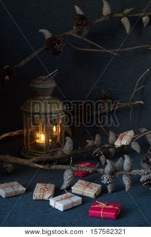 Christmas gifts, rowan, nuts, old lamp and pine branch with cones on dark surface